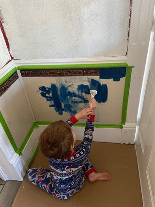 Oldest son helping paint over old wallpaper border for modern blue kitchen makeover
