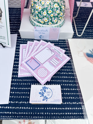 Stack of pink cards with a business card on a blue patterned surface Daily planner with various sections on a pink background scalloped border cute pretty dopamine coquette cutesy day to-do list notebook adhd friendly checklist life hack kawaii small business bows mental health journal gratitude practice daily planner