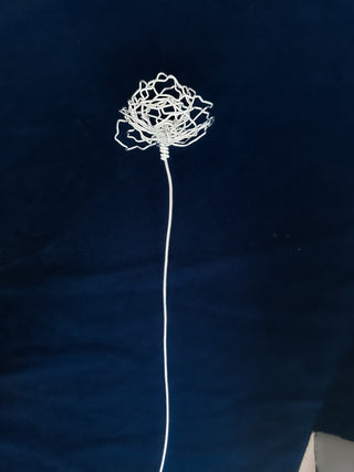 A cluster of three silver wire flowers with intricate, openwork petals. The stems are long and slender, and the flowers are arranged in a bouquet. The background is a solid, dark blue. carnation January birth flower preserved florals Mother’s Day gifts gift for mom silver and black wire flowers delicate pretty decor wedding floral preservation forver flowers wire flower stem carnations curved leaf handmade small business steel aluminum petals dried florals whimsical decor
