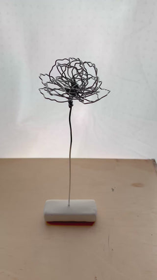 A cluster of three silver wire flowers with intricate, openwork petals. The stems are long and slender, and the flowers are arranged in a bouquet. The background is a solid, dark blue. carnation January birth flower preserved florals Mother’s Day gifts gift for mom silver and black wire flowers delicate pretty decor wedding floral preservation forver flowers wire flower stem carnations curved leaf handmade small business steel aluminum petals dried florals whimsical decor