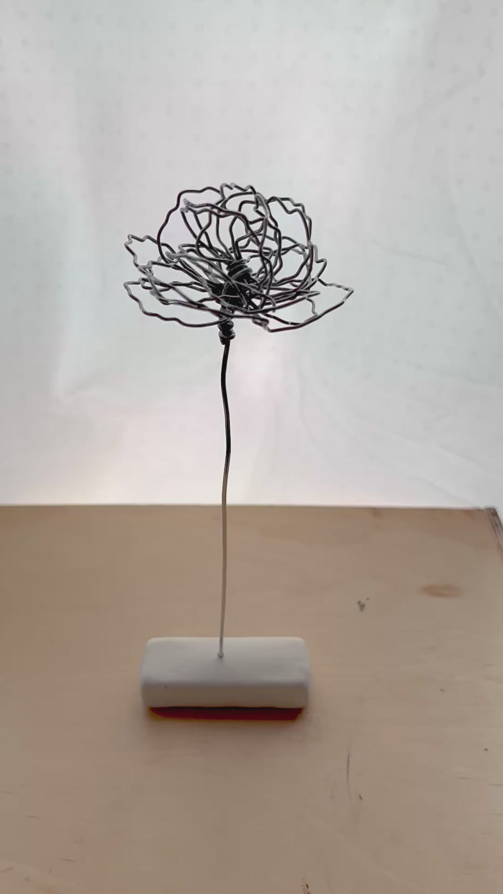 A cluster of three silver wire flowers with intricate, openwork petals. The stems are long and slender, and the flowers are arranged in a bouquet. The background is a solid, dark blue. carnation January birth flower preserved florals Mother’s Day gifts gift for mom silver and black wire flowers delicate pretty decor wedding floral preservation forver flowers wire flower stem carnations curved leaf handmade small business steel aluminum petals dried florals whimsical decor